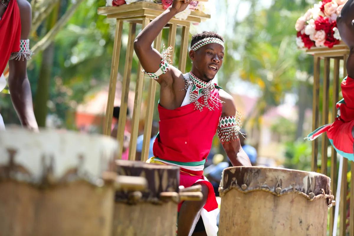 A performer dancing beside traditional African drums